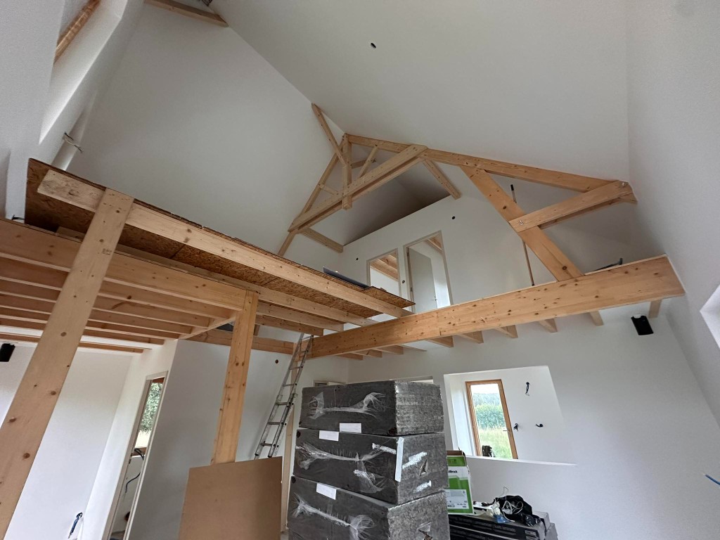 Grand volume sous charpente, murs et plafonds blancs, poutres apparentes